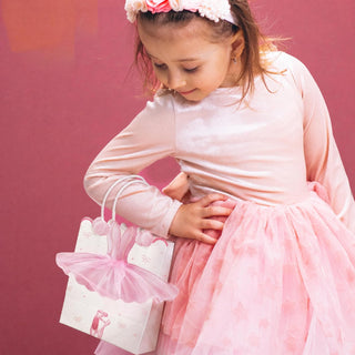 Ballerina-themed gift bag held by child, white with pink tutu decoration and ribbon prints