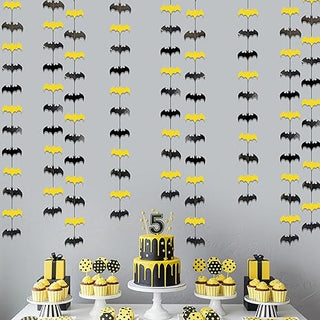 Black and yellow bat wall decorations above a birthday cake setup