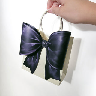 Handheld cream gift bag with large dark satin bow and white rope handle