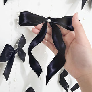 Black ribbon bow garland with pearl bead strings, held in hand