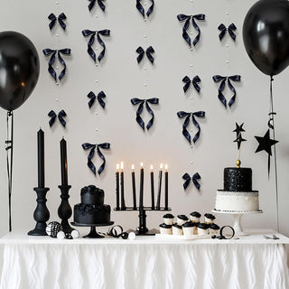 Black bow garland decorations with pearl strings hanging for a party backdrop