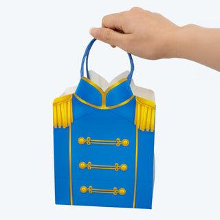 Blue party gift bag held by hand, gold trim, tassel handles and emblem