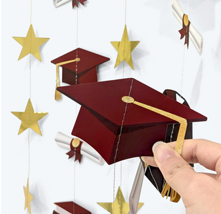 Hand holding graduation cap garland piece with gold tassel and star accents