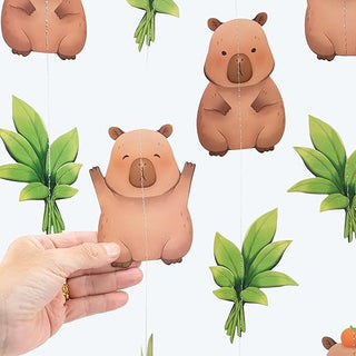 Hanging capybara garland with tan capybara figures and green leaf cutouts on strings