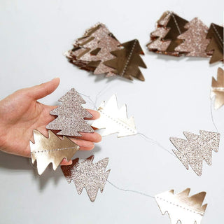 Hand holding glittery pine tree garland pieces in champagne gold and silver