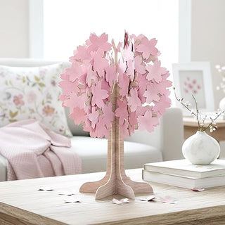 Cherry blossom tree centerpiece with pink blossoms, wooden trunk base, and petals on table