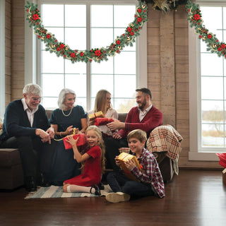 Holiday garland wreath with red flowers and gold ornaments hanging over window
