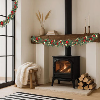 Christmas garland on mantel shelf with red flowers and gold ornaments by fireplace