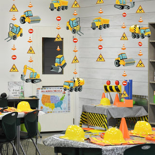 Construction truck garland on a wall with yellow vehicles, orange cones, and yellow caution signs