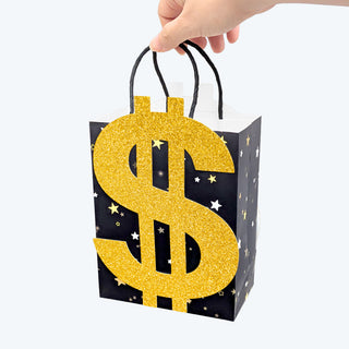 Dollar-themed gift bag held by hand, black with glitter gold dollar sign and star accents.