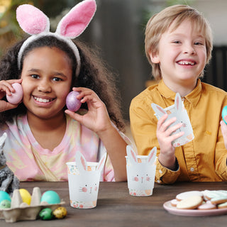 Easter bunny paper cup sleeves, with Easter cups in Easter eggs and flowers pattern, held by kids at an Easter party