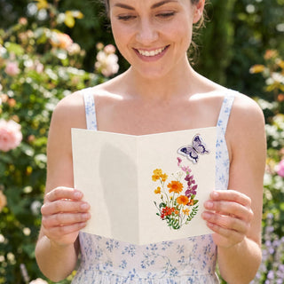 Person holding floral butterfly greeting card with colorful bouquet and butterflies
