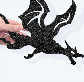 Black glitter dragon cutout banner held by hand on light background