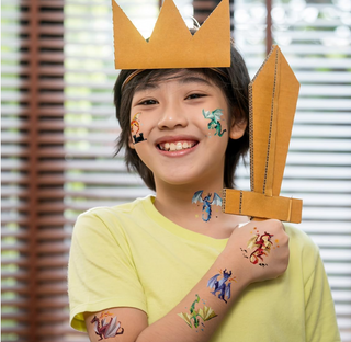 Temporary dragon tattoos on child’s face and arms, geometric shapes in blue and red