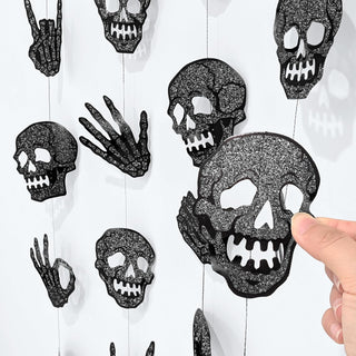 Close-up of black glitter skull cutouts and hand shapes on the garland