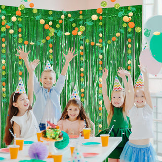 Green glitter fringe curtain backdrop with dinosaur-themed hanging garland