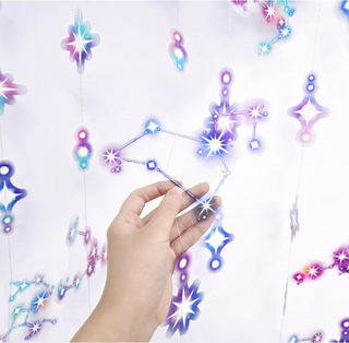 Hand holding a star-shaped constellation decoration piece to attach to hanging string