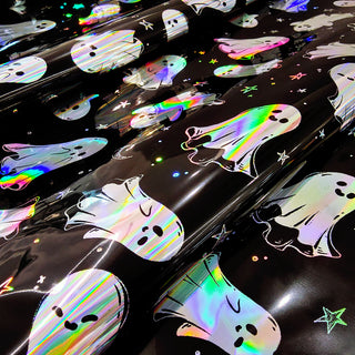 Close-up of glossy iridescent Halloween ghost wrapping paper on a dark black base