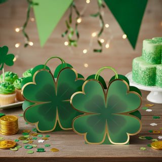 Clover-shaped green gift bags with gold edging and handles, arranged on party table