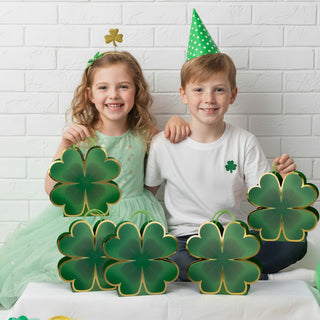 Green clover-shaped gift bags with gold trim and handles, held by children