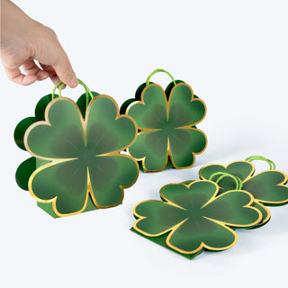 Two clover-shaped green gift bags with gold-edged outlines and loop handles