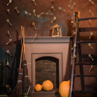 Gold key garland draped over fireplace with hanging keys and orange pumpkins