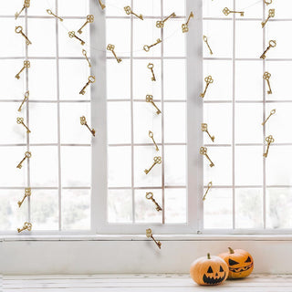 Gold key garland on large window panes, keys evenly spaced across view