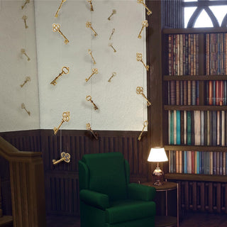Gold key garland on wall above green armchair and bookshelf