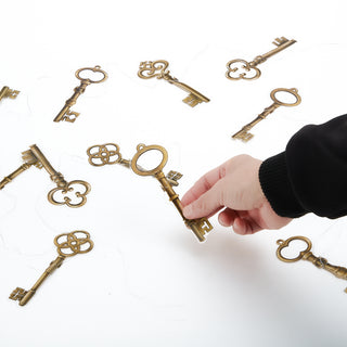 Gold key garland on white surface, hand holding a hanging key