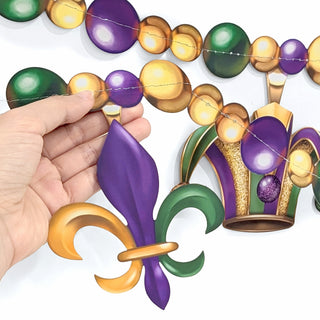Hand holding a Mardi Gras bead garland with purple and gold fleur-de-lis charms