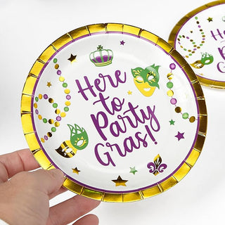 Mardi Gras paper plate held in hand, gold rim with "Here to Party Gras!" purple lettering