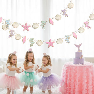 Pastel undersea banner garland hanging behind a birthday cake and table