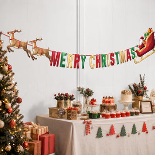 Christmas banner draped above a party table, with “Merry Christmas” and Santa sleigh