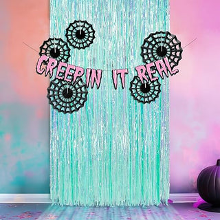 Teal fringe Halloween backdrop with black spider web cutouts and 'GREEPIN IT REAL' text