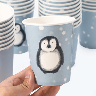 Single blue paper cup with penguin illustration, held in hand