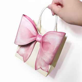 Hand holding a pink gift bag with big satin bow and rope handle