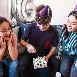 Friends at party opening a small present wrapped in pixel game icons paper