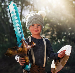 Child holding long sword foil balloon with teal-and-brown check and argyle pattern
