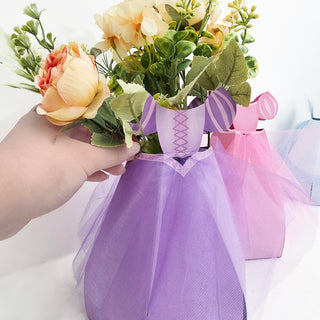 Hand arranging flowers inside a purple flower centerpiece bag with bow trim