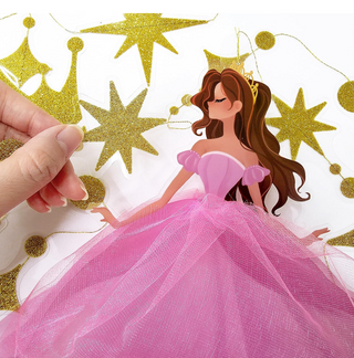 Hand attaching gold star crown garland to a pink princess dress cutout on hanging strings