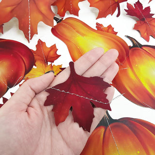 Close-up of fall leaf ornament on garland string with attached pumpkin shapes