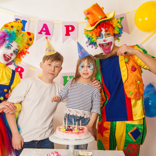 Kids and clown wearing colorful rainbow party hats with pom poms