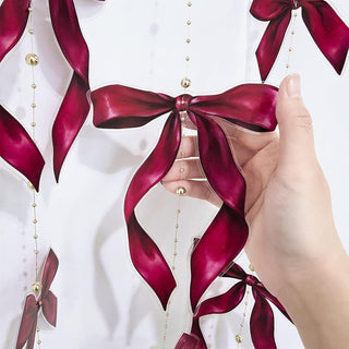 Red ribbon bow garland detail with gold bead chain and satin bow loops