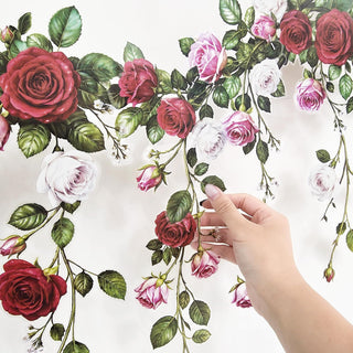 Floral rose garland banner with green leaves and pink and red roses, being adjusted