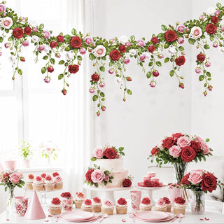 Floral rose garland banner backdrop above desserts with rose cupcakes and pink tableware
