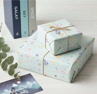 Rocket pattern gift wrap set with tied packages and ribbon, pastel planets and stars