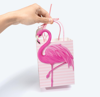 Pink flamingo gift bag with striped design and ribbon handle, held by hand