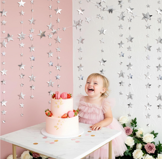Silver star garlands kit with hanging silver star strands behind celebration cake