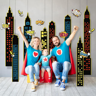 Superhero party backdrop with tall skyline panels and wall stickers featuring POW, BAM, WOW