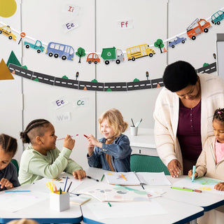 Curved transport road banner with buses, trucks, cars, and trees above a classroom table